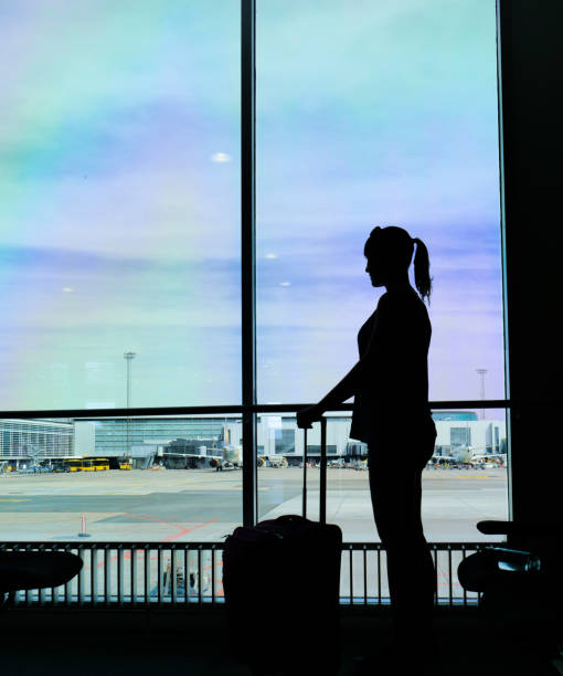 istock SILHOUETTE: Female passenger looking through the large window before her flight. 1182231786
