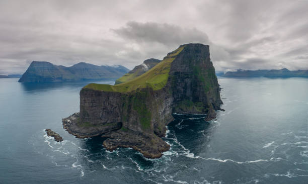 istock AERIAL: Flying around small grassy island with scenic mountains and cliffs. 1182235640