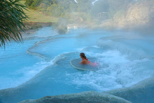 istock Young woman rests on a white stone ledge in invigorating thermal baths in Italy. 1182237140
