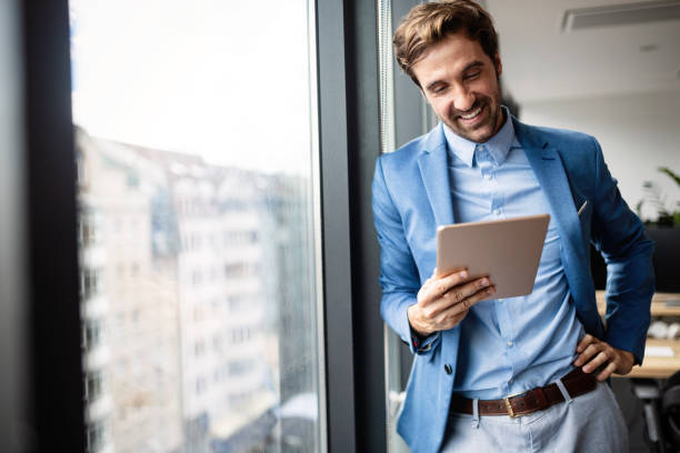 portrait of businessman smiling while using digital tablet - businessman one man only standing elegance imagens e fotografias de stock