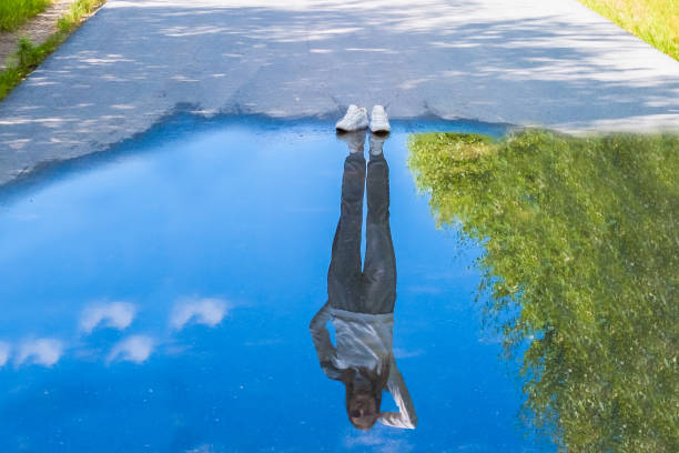 odbicie osoby stojącej w pobliżu kałuży. styl jest odzwierciedleniem twojej postawy i twojej osobowości. pojęcie samotności - puddle street water women zdjęcia i obrazy z banku zdjęć