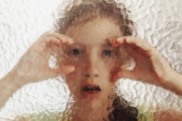 istock Young scared girl behind glass with her hands on it 1182245105