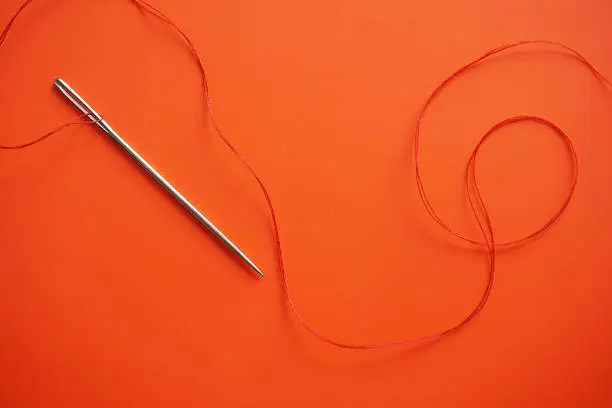 Direct Above Shot of needle and red thread. Minimal Aesthetics.