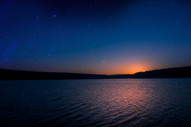 sunset with starry sky over a lake stock photo