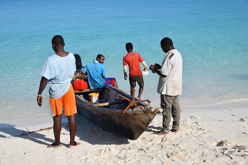 Kendwa, Zanzibar - October 6, 2019: Group of local fishermen near wooden boat getting ready to go to sea. Tanzania, Africa