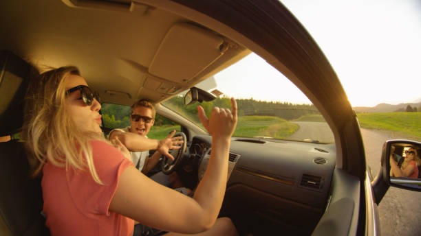 close up: vue latérale d'un jeune couple dansant dans leur voiture pendant qu'ils conduisent. - side view mirror audio photos et images de collection