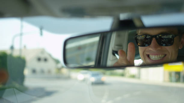 istock CLOSE UP: Young male driver adjust his rear view mirror and looks at himself. 1182247643