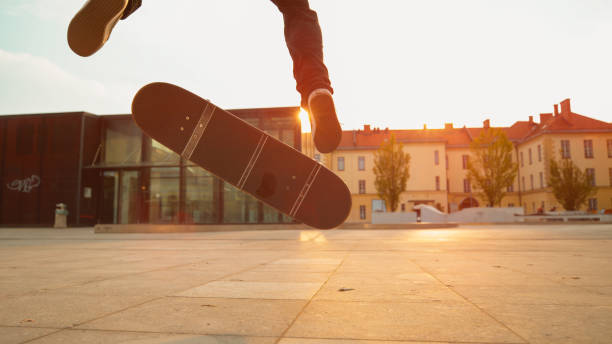 primo tempo: scatto cinematografico dello skater maschile che atterra un fakie in una serata di sole. - fakie foto e immagini stock