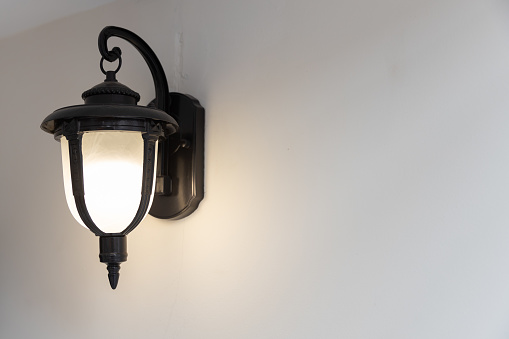close up view of single classic black lamp or lantern on white wall with copy space.