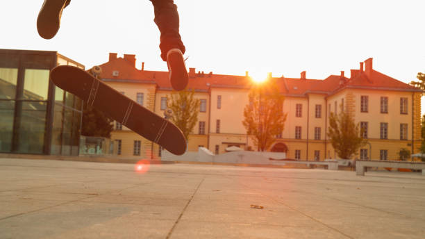 primo: il tizio skater irriconoscibile fa un fakie in una piazza della città al tramonto - fakie foto e immagini stock