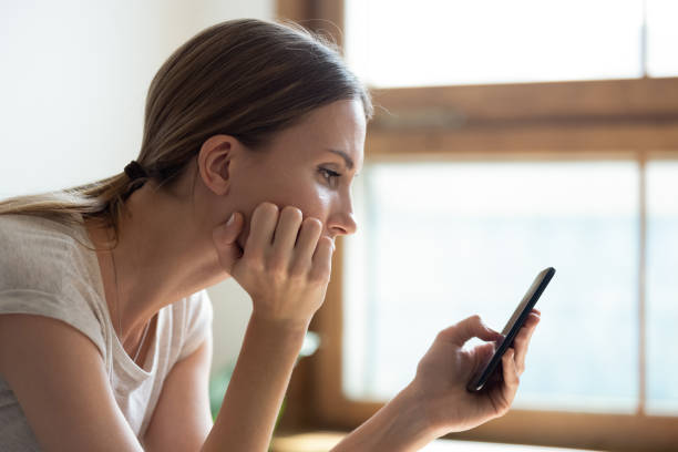 pensive triste joven mujer sosteniendo teléfono inteligente esperando sms de novio - addiction smart phone internet social networking fotografías e imágenes de stock