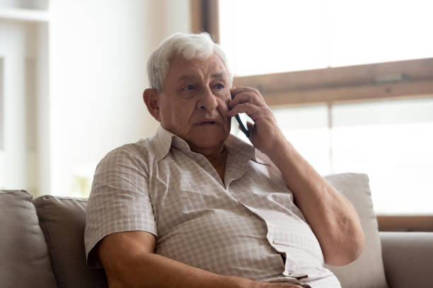 l'anziano parla al telefono con una comunicazione lontana con il medico - telephone worried one person discussion foto e immagini stock