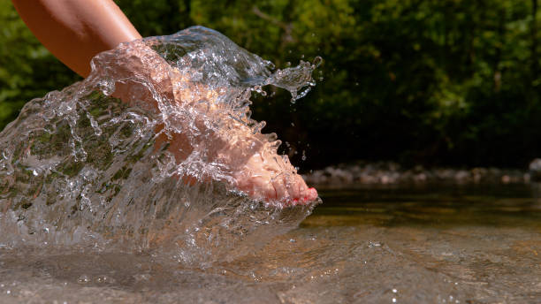 istock CLOSE UP: Unknown young woman's bare foot splashing the crystal clear water. 1182249558