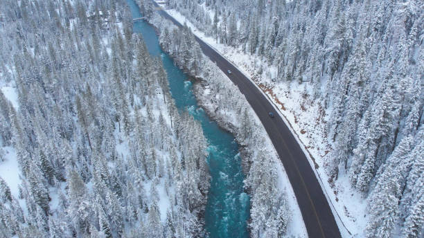 istock AERIAL: Emerald river rushing through the snow covered forest along busy road. 1182249675
