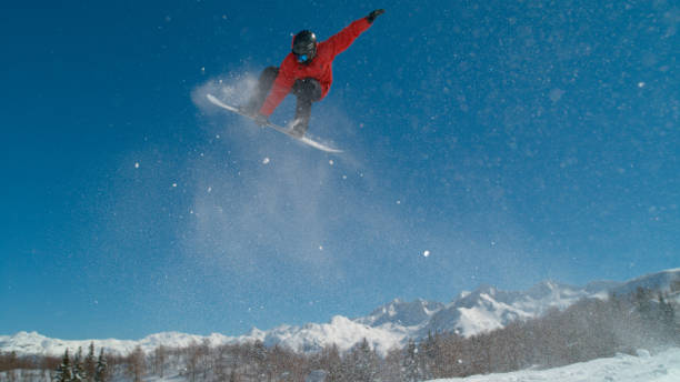 istock Professional snowboarder leaves a trail of snow while jumping off a kicker. 1182249901