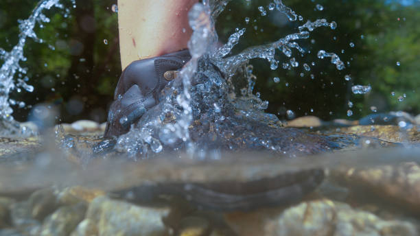 istock HALF UNDERWATER: Unknown female hiker splashing water by stepping into the river 1182249945
