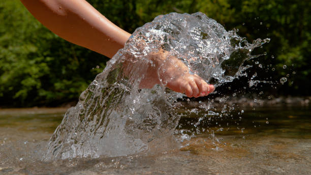 istock CLOSE UP: Unknown barefoot girl kicks and sprays the refreshing river water. 1182249966