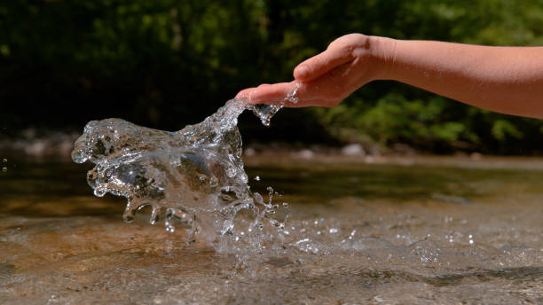 istock CLOSE UP: Unknown young woman's hand splashes the crystal clear river water. 1182249967