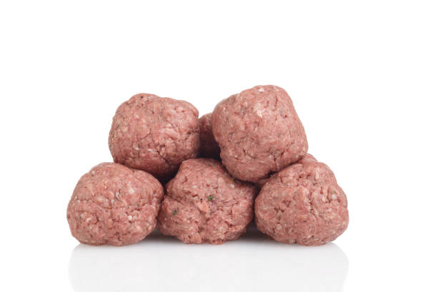 closeup pile of raw meatballs on white