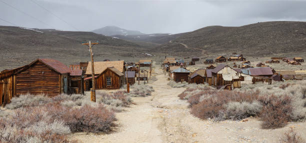 istock Empty gravel road runs through a ghost town in the harsh American wilderness. 1182250097
