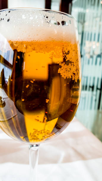 Beer poured into a glass is on the table with a white tablecloth in the restaurant