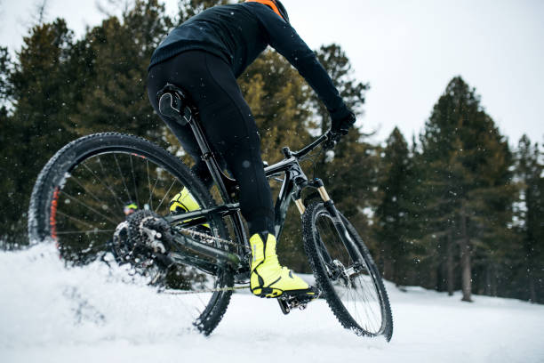 istock Midsection of mountain biker riding in snow outdoors in winter. 1182254895