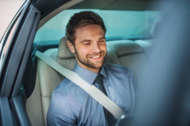 istock Businessman with tablet sitting on back seats in car, working. 1182258206