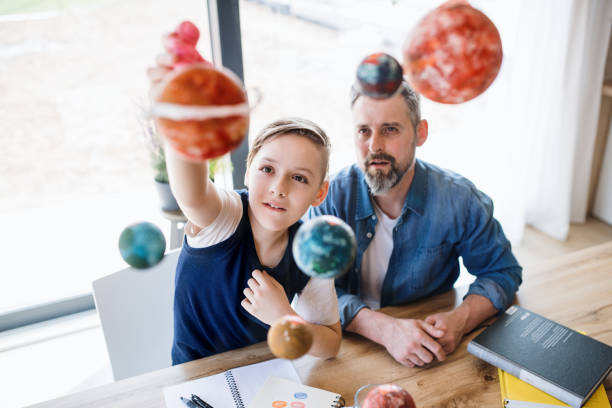 istock Mature father with small son sitting at table indoors, working on school project. 1182259825