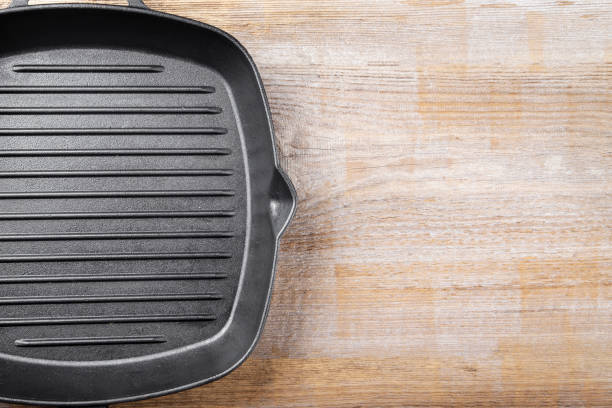istock New empty cast-iron grill pan with two handles on a wooden background. 1182260815