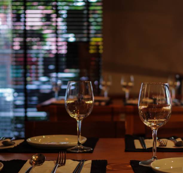 istock Restaurant table with empty wine glasses, forks, knives and black tablemat 1182269429
