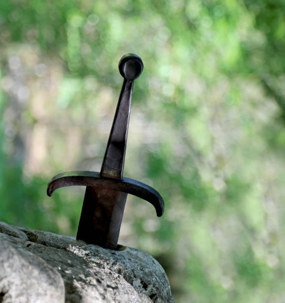 istock Sword in the stone and green background 1182273393