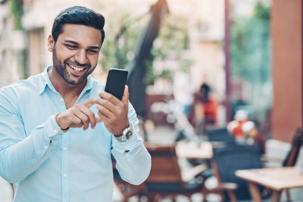 istock Smiling man walking and texting outdoors in the city 1182280265