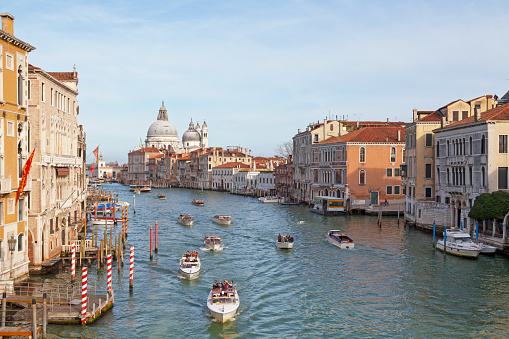 Famous canal within Venice showcasing multiple boats, including gondolas as well as some of the beautiful buildings Venice has to offer.