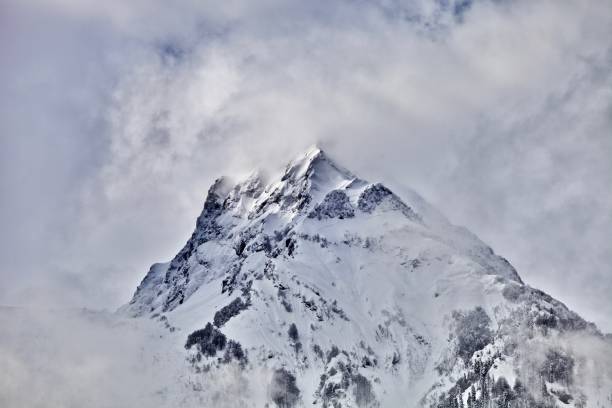 istock White snowcapped single mountain top among the clouds 1182288461