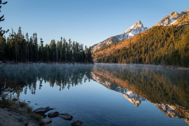 istock Dawn Over Lake Reflecting Trees and Mountains 1182289415