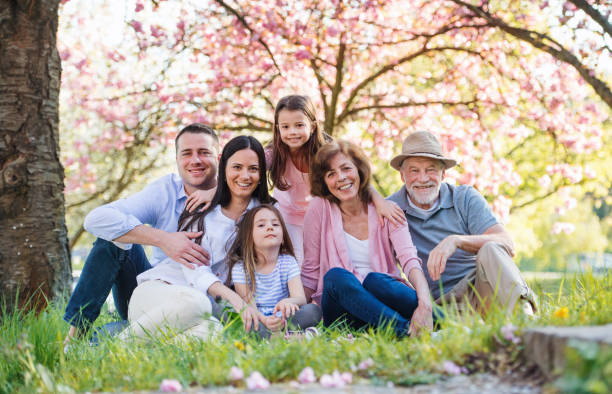 istock Three generation family sitting outside in spring nature, looking at camera. 1182290967