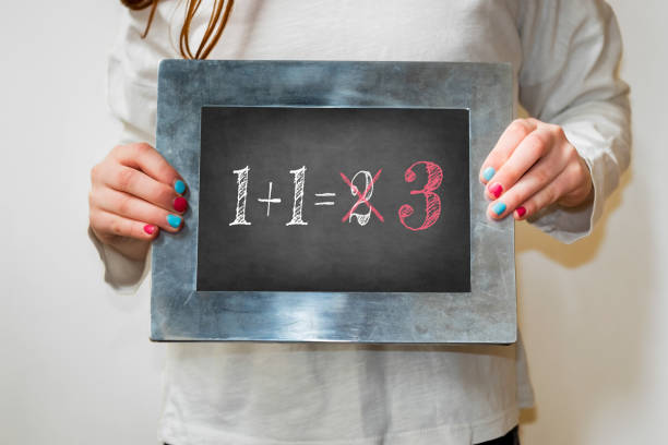 Child holding a blackboard with the text 1+1=3 stock photo