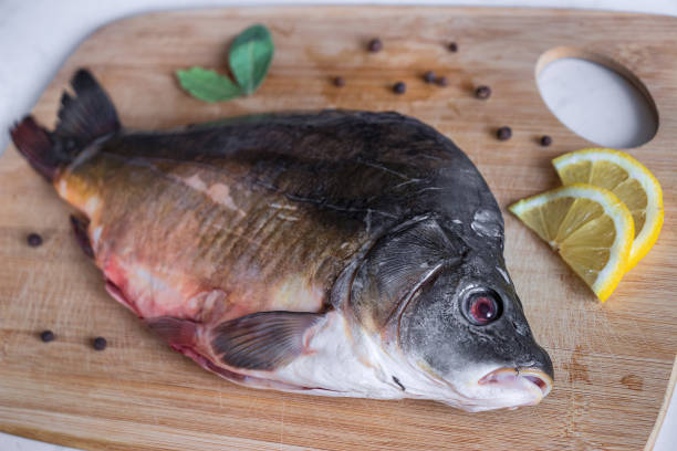 istock Raw mirror carp with peppers and lemon on cutting board. Cooking fish. Focus on foreground 1182294406