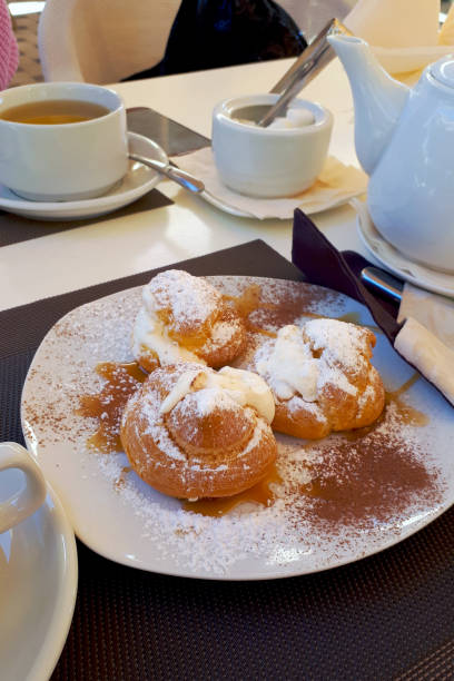 istock Sweet puff pastry, fresh and covered with powdered sugar on a gray table next to the kettle and cups for tea 1182304868