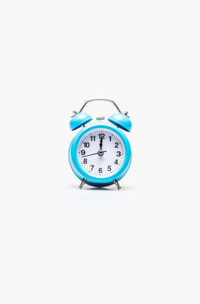 istock Right timing. A light-blue alarm clock with a black and white clock face, placed on a white background. Clock hands show 12 o’clock. 1182305216