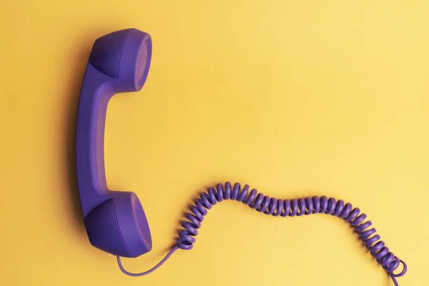 istock Purple telephone receiver on yellow background 1182306052