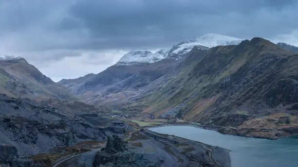 Photo of Beautiful landscape image of Dinorwig Slate Mine and snowcapped Snowdon mountain in background during Winter in Snowdonia with Llyn Peris in foreground