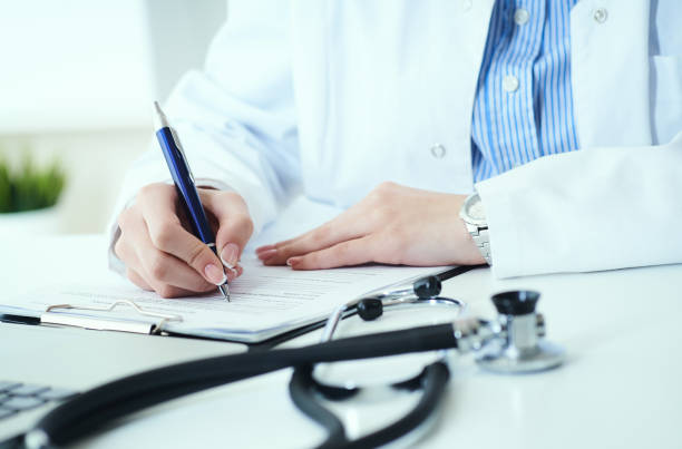 mid section of female doctor writes prescription to patient at worktable. panacea and life save, prescribing treatment. - healthcare and medicine stethoscope patient report imagens e fotografias de stock