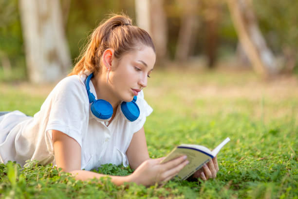 istock Smiling woman relaxing in grass and reading a book. 1182313625