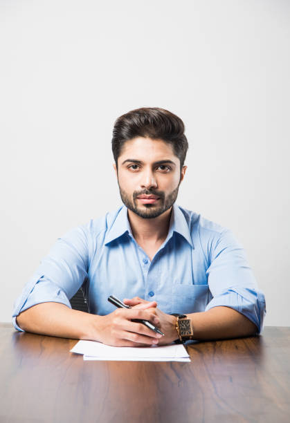 istock Indian businessman writing a document while sitting at desk or work station 1182314065