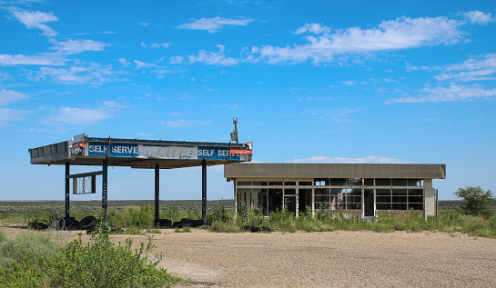 gas station from the 70's abandoned in the desert panhandle of Texas along Route 66, backed with a bright blue sky and emptiness