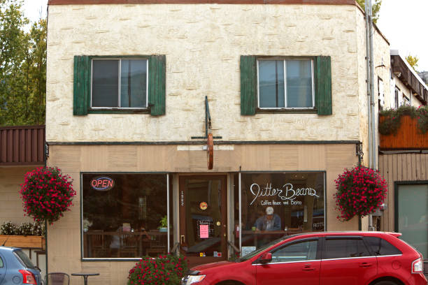 Lumby, British Columbia, Canada- September 25,2019:  Front of small business coffee shop . Worn and old looking. Cars parked in front. Hanging flower baskets on building.