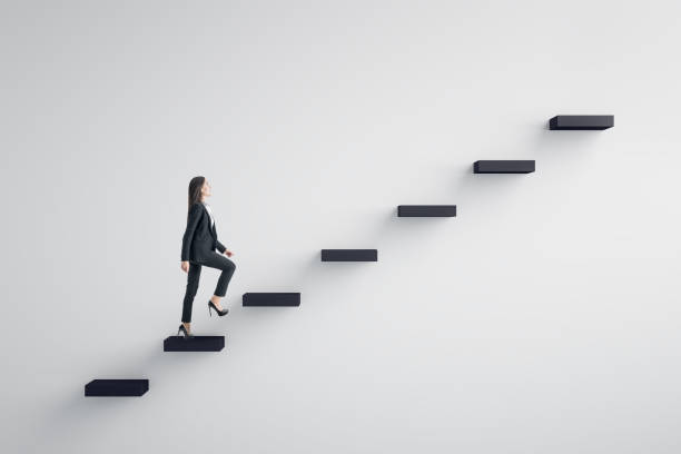 Leadership and career development concept Side view of young businesswoman climbing stairs to success on concrete wall background. Leadership and career development concept staircase stock pictures, royalty-free photos & images