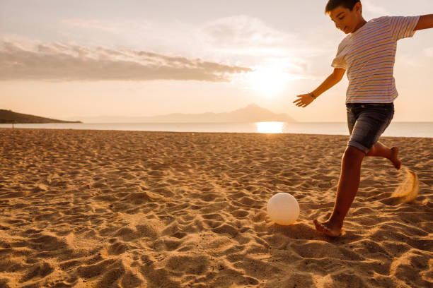 istock Boy playing soccer on the beach 1182330781