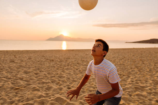 istock Boy heading soccer ball on the beach 1182330794